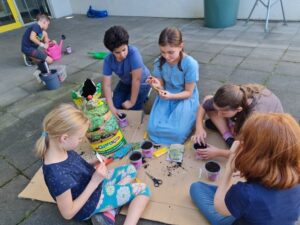 Kinder sitzen auf dem Boden und füllen Töpfe mit Blumenerde