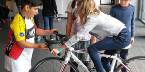 Ein Mädchen sitzt auf einem Fahrrad, ein Junge hält das Fahrrad, damit sie nicht umkippt