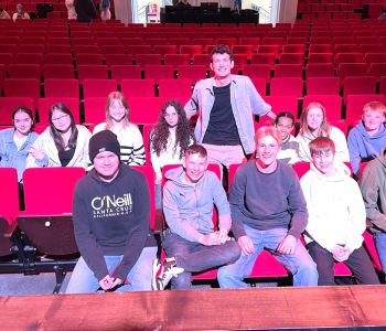 Eine Gruppe Schülerinnen und Schüler in einem Theater mit roten Sesseln.